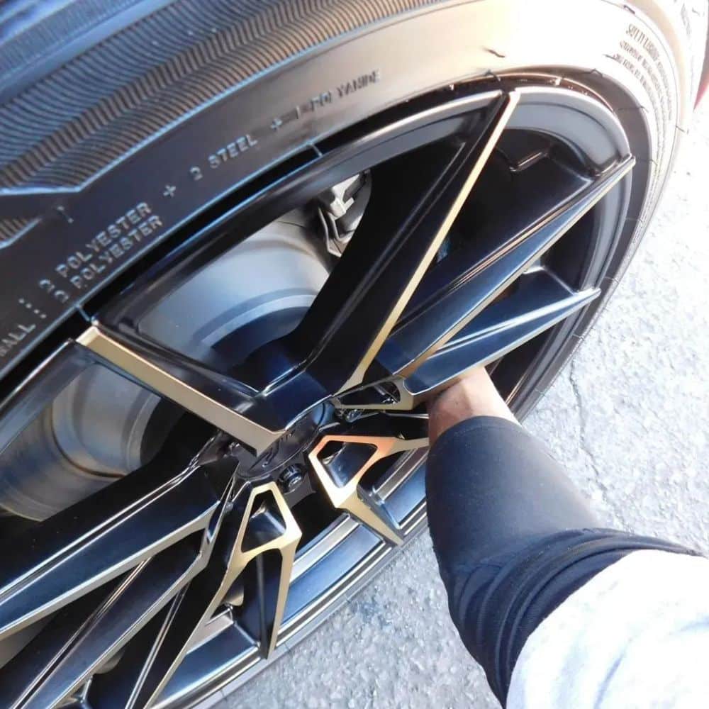 The owner clean a tire rim during a mobile auto detailing session.